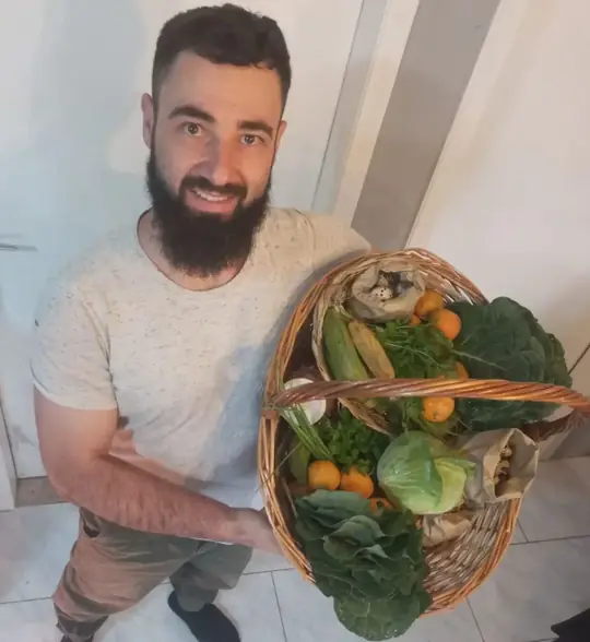 Aluno segurando uma cesta cheia de alimentos colhidos